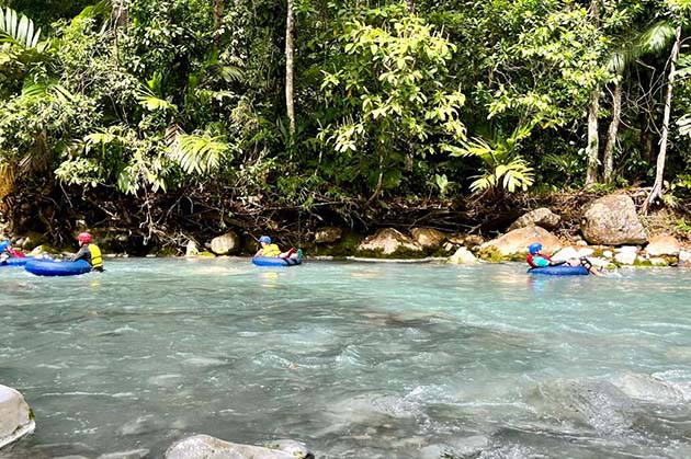 Participants in the Tubing in Rincón de la Vieja float along a crystal-clear river, surrounded by the verdant foliage of the area's enchanting forest.