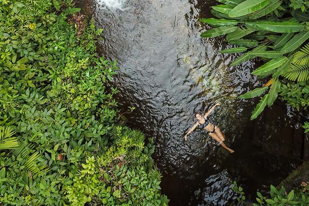 Floating serenely on their back in a narrow, tree-lined stream, surrounded by the lush greenery of Rincon de la Vieja.